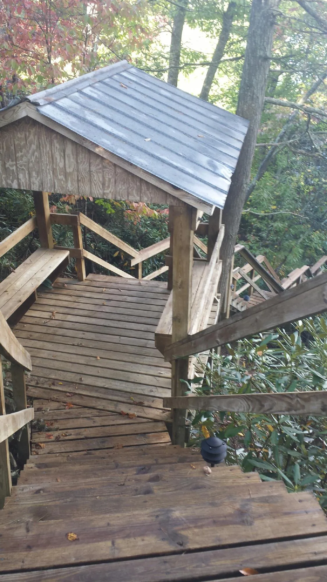 Metal roofed shelter over wooden steps on a wooded walkway — Skylight Repair & Installation work by our crew in Freeman