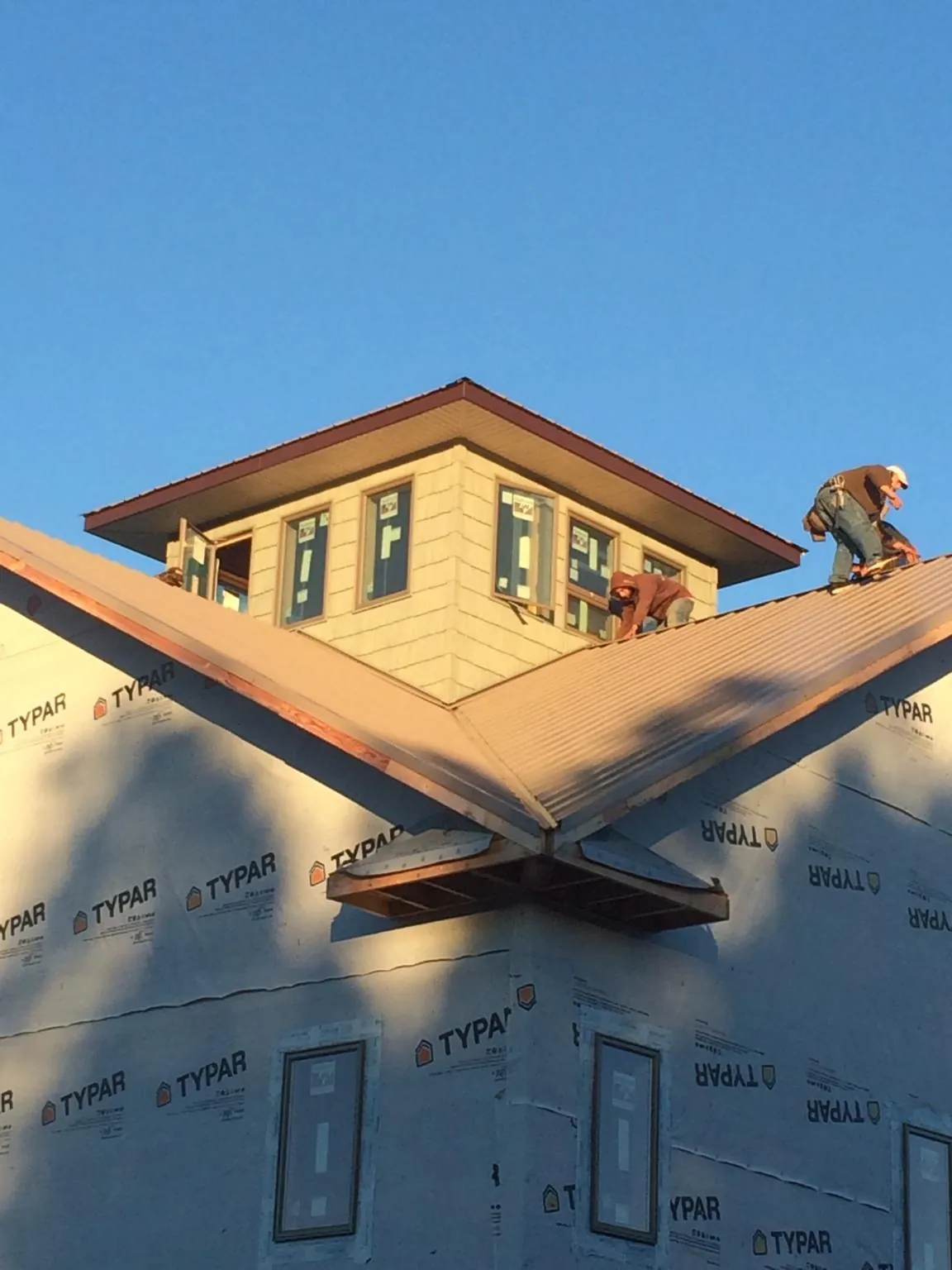 Roofers working around a rooftop cupola on a new metal roof at sunset — Roof Waterproofing in Freeman by Roofing Brothers